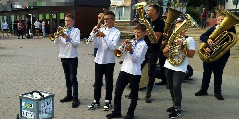 Kinder mit Blasinstrumenten und in ukrainisch bestickten Hemden spielen auf Blasinstrumenten auf der Straße