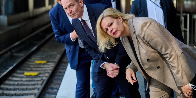 Faeser und Wissing beugen sich an einem Bahnsteig vor