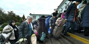 Viele Menschen erklimmen mit vollem Gepäck die Treppe auf einem Bahnhof