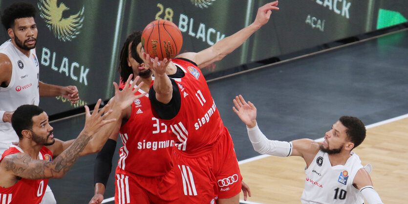 Basketballspieler springen vorm Korb nach dem Ball