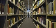 Ein Mann steht in einem Gang in eienr Universitäts-Bibliothek.