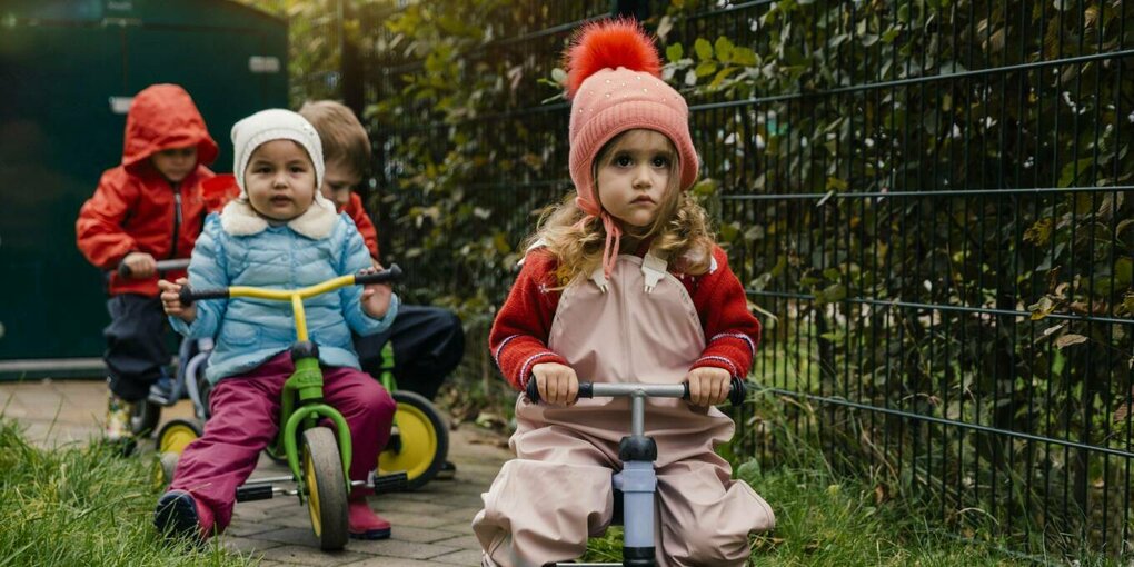 Kinder mit Mützen auf Rollern