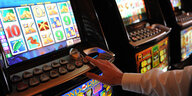 Eine Hand an einem Spielautomaten eines Kasinos.