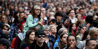 Ein Mädchen mit hellgrünem Pullover sitzt auf den Schultern eines Mannes und ragt aus einer Demonstrationsmenge empor