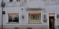 2 Fensterscheiben , eine mit Gardine, Lampen neben dem Eingang eines Wirtshauses