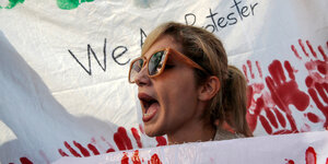 Demonstrantin mit Transparent voll roter Hände am Montag in Istanbul