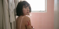 Eine junge Frau in einem Badezomer mit einem roten Kreuz auf der Schulter