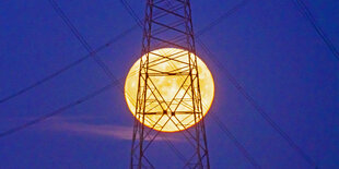 Vollmond scheint vor einem Strommast