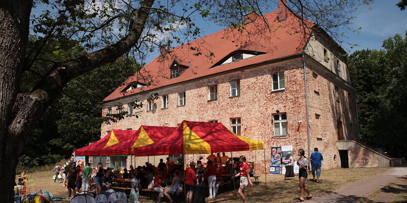 Ein altes Haus ohne Putz, davor Festzelte