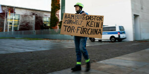 Demonstrant hält ein Pappschild "Hamburg das Tor zur Welt kein Tor! für China"