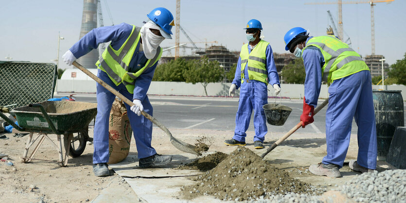 3 vermummte Bauarbeiter in Arbeitskleidung und Schutzhelm schaufeln