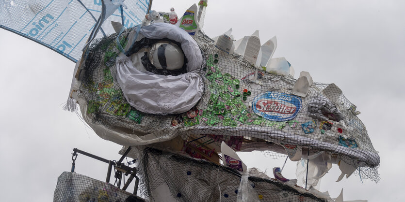 Ein aus Plastikmüll nachgebildeter Drachenkopf; Greenpeace-Aktivist*innen haben ihn für einen Protest gegen Nestlé in der Schweiz gebaut