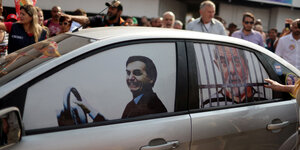Bolsonaro ist als Fahrer auf eine Autoscheibe geklebt, Lula ist hinter Gitter geklebt