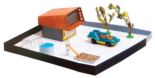 Ein (futuristisches) Häuschen, ein (Elektro-)Auto, eine Rutsche, ein Pool, zwei Kaktusse in der Optik von Modelleisenbahnzubehör