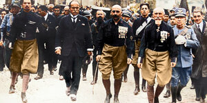 Historisches Foto: Mussolini im Anzug maschiert in Rom ein, neben ihm Männer in schwarzen Hemden
