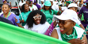 Gut gelaunte Frauen in Lesotho im Wahlkampf halten ein grünes Plakat