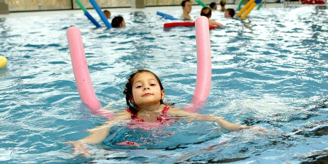 Ein Mädchen lernt Schwimmen mit einer Schwimmnudel.