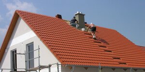 Zwei Männer decken das Dach eines Fertighauses