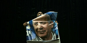 Ein Anhänger hält ein Plakat von Benjamin Netanjahu bei einer Wahlkampfveranstaltung in die Höhe