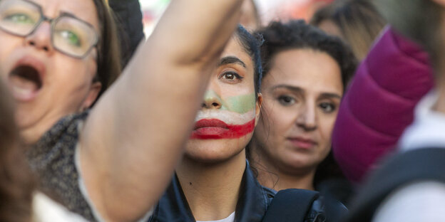 Frauen demonstrieren mit der iranischen Flagge aufs Gesicht geschminkt