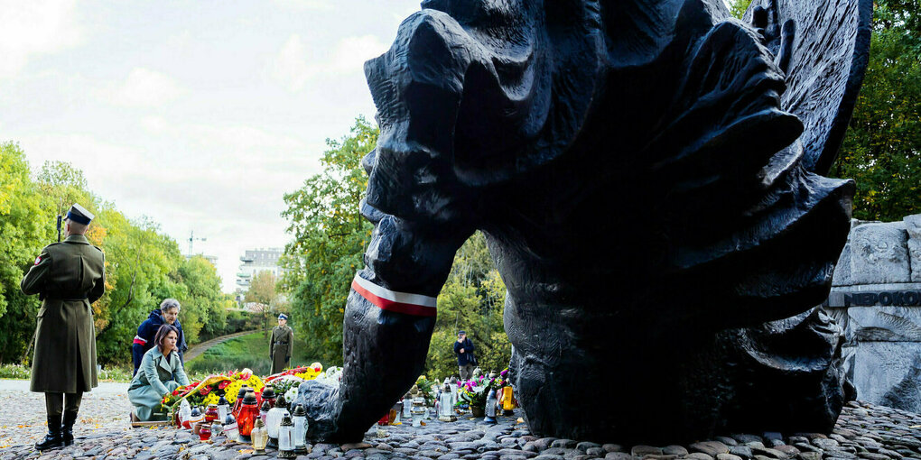 Baerbock legt Blumen an einem rießigen Denkmal nieder