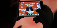 Jemand hält ein Smartphone, auf dessen Display Präsident Erdogan dabei zu sehen ist, wie er eine Rede hält.