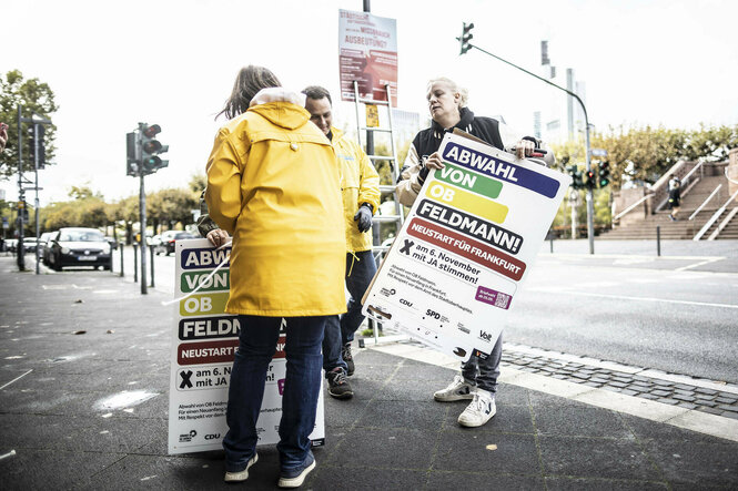 Personen mit Plakaten, die für die Abwahl von OB Feldmann werben, an einer Straße