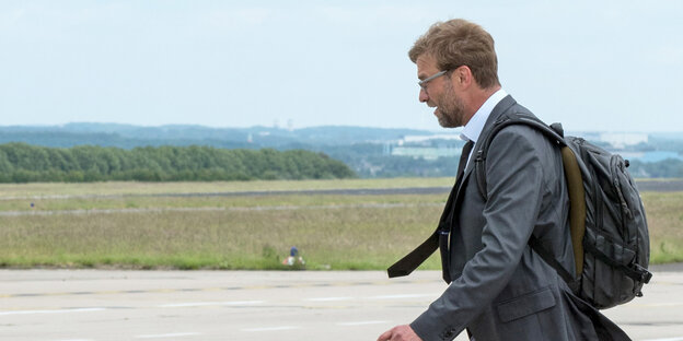 Jürgen Klopp, mit Rucksack, geht auf dem Rollfeld in Dortmund zum Flugzeug.