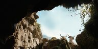 Blick aus den Tiefen einer großen Höhle hinaus auf den Himmel und die Umgebung