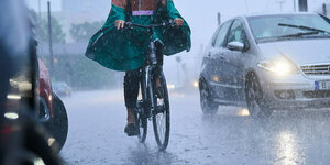Radfahrerin und Auto im Regen