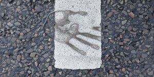Handabdruck nach einer Klebeaktion auf dem Straßenpflaster