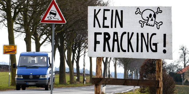 Eine Landstraße mit Auto und daneben ein Plakat "Kein Fracking"