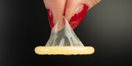 Ein Kondom wird mit zwei Fingern gehalten.