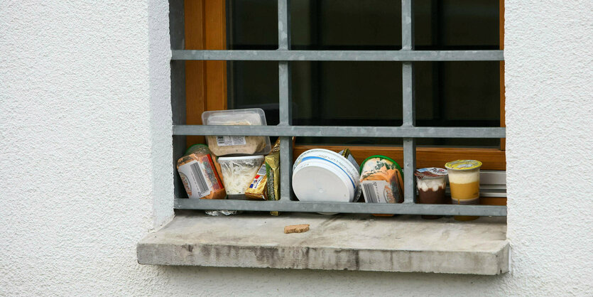 Lebensmittel stehen an einem vergitterten Fenster zur Kühlung