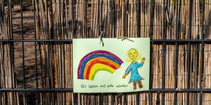 Kinderzeichnung eines Regenbogens und einer Person, die winkt