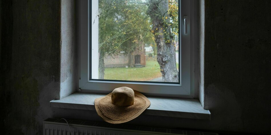 ein Hut liegt auf einer Fensterbank, draußen ist eine Kirche zu erkennen