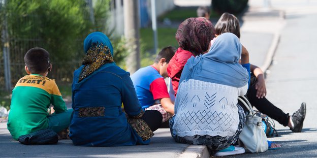 Flüchtlinge sitzen auf dem Bürgersteig