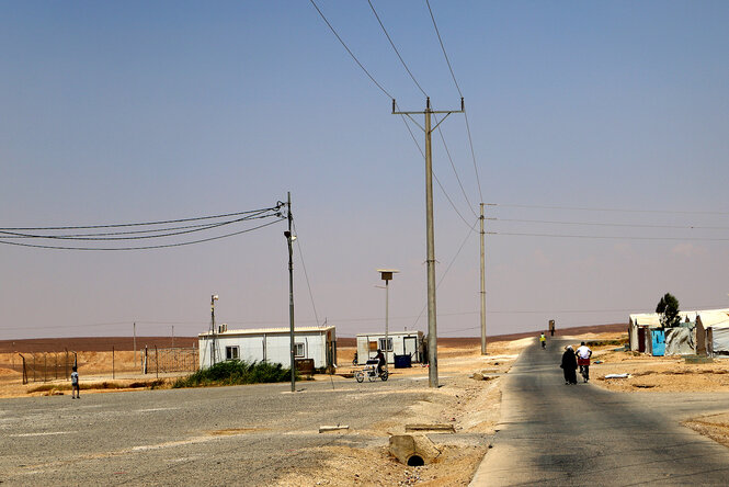 Eine Straße durch eine wüstenähnliche Landschaft, vereinzelte Wellblechhütten