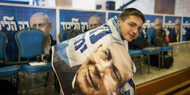Eine Junge umhüllt in einem Plakat, das Benjamin Netanjahu zeigt