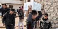 Ein Junge trägt ein Paket mit Hilfslieferungen der UN auf dem Kopf