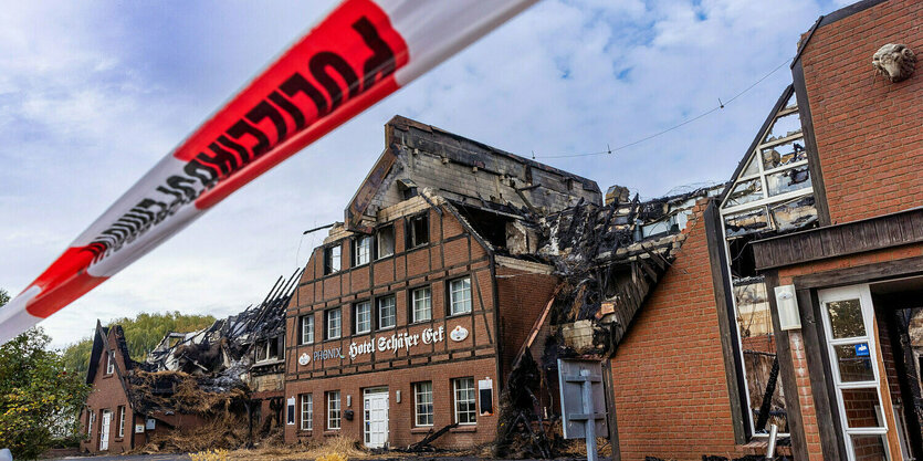 Rot-weißes Absperrband vor einem niedergebrannten Wohnhaus