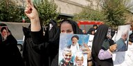 Eine Frau hält ein Plakat mit Fotos Generälen aus dem Iran