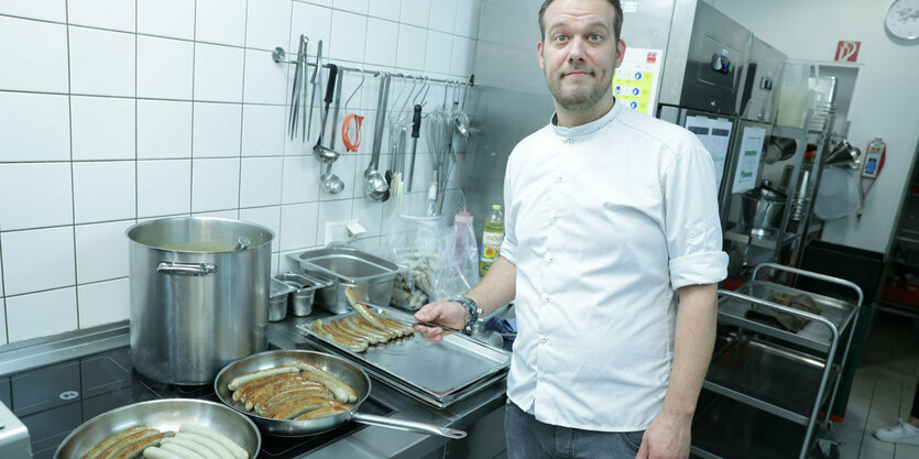 Ein Koch steht mit einer Pfanne in der Küche