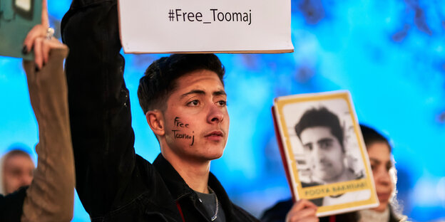 Ein mann hält ein Protestplakat auf dem "#Free Toomaj" zu lesen ist