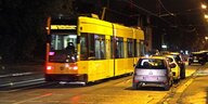 Straßenbahn und parkende Autos in einer nächtlichen Straße