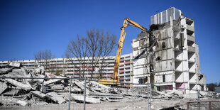 Ein Bagger reißt gerade einen Plattenbau ab