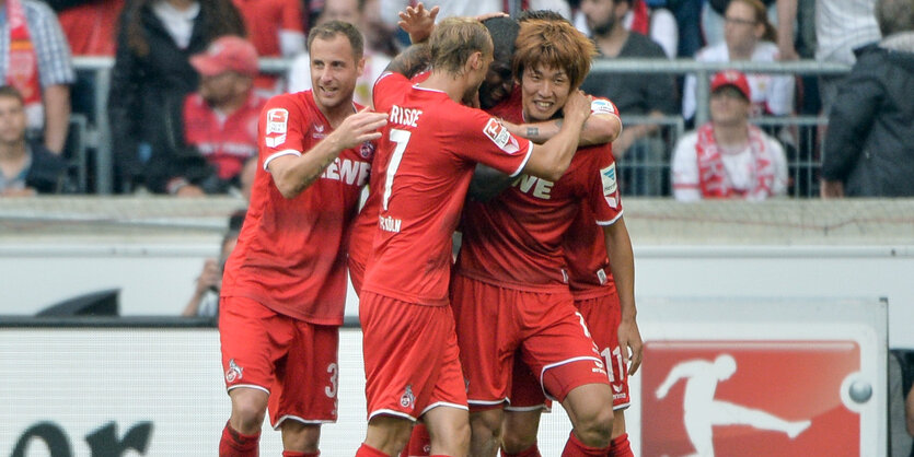 Die Kölner spieler umarmen Yuya Osako (r) nach dem Tor zum 1:3.