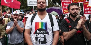 Ein Mann trägt ein queerfeindliches T-shirt, er steht in einer Menschenmenge, die Menschen tragen türkische Fahnen und Plakate