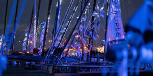 mehrere Segelboote mit Fahnen an den Masten in blauem Licht