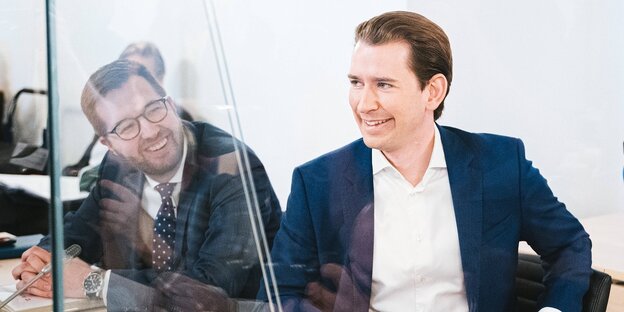 Sebastian Kurz lacht, neben ihm sitz - durch eine Glasscheibe getrennt von ihm - Thomas Schmid